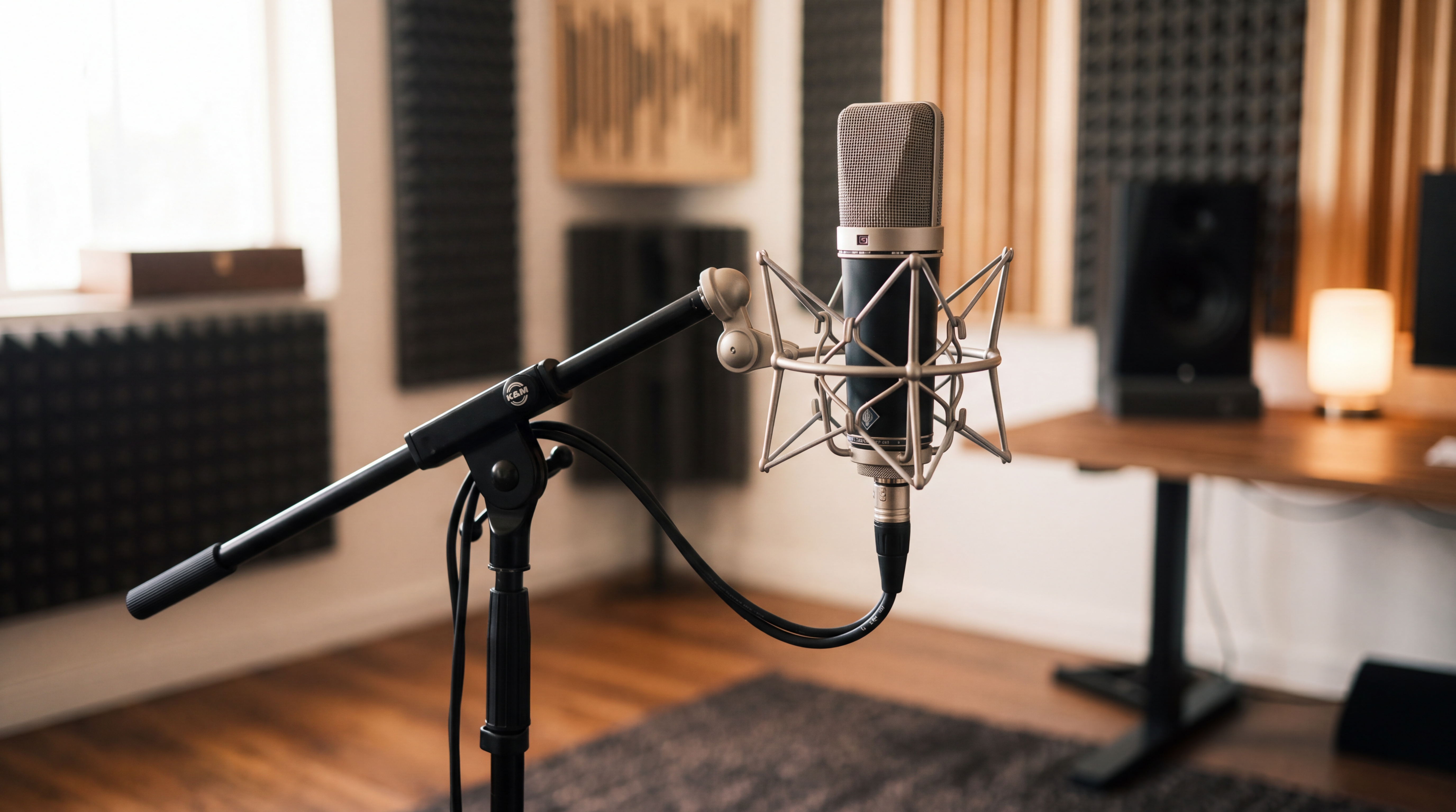 A professional condenser microphone on a sleek stand in a minimalist, modern studio with warm lighting